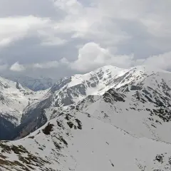 Kasprowy Wierch zimą, ośnieżone szczyty Tatr pod pochmurnym niebem.