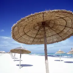Słomiane parasole na pustej plaży w Tunezji. W marcu pogoda już zachęca do wypoczynku.