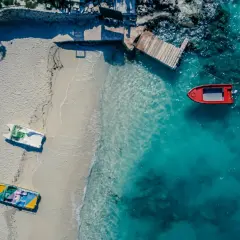 Plaża w Albanii z łodziami na piasku i w turkusowej wodzie. Jakby golem albania czekał na przygodę.