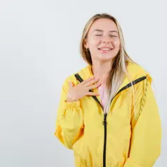Uśmiechnięta dziewczyna w żółtej kurtce softshell. Dowiedz się, jak prać softshell, by zachować jego właściwości.