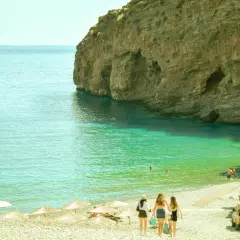 Kreta, sierpień: trzy dziewczyny idą na plażę z turkusową wodą i skalistymi klifami. Idealna pogoda na wakacje.