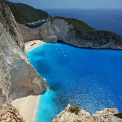 Widok na Zatokę Wraku na Zakynthos, Grecja. Wrak statku leży na piaszczystej plaży otoczonej białymi klifami i turkusowym morzem.