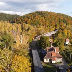 Góry jesienią, gdzie są? Widać kolorowe drzewa, most kolejowy i domy.