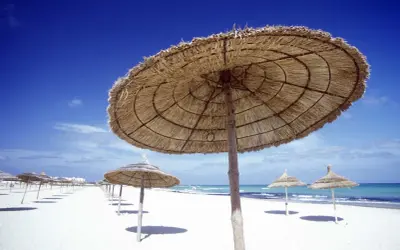 Słomiane parasole na pustej plaży w Tunezji. W marcu pogoda już zachęca do wypoczynku.