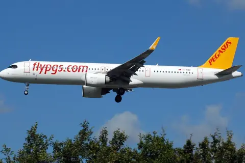 Samolot Pegasus Airlines z napisem "flypgs.com" na kadłubie, gotowy do lądowania. W bagażniku rejestrowanym czeka na pasażerów.