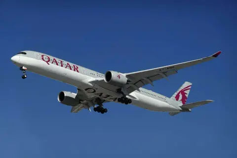 Samolot Qatar Airways z wysuniętym podwoziem, gotowy do lądowania. Idealny do przewozu bagażu podręcznego.