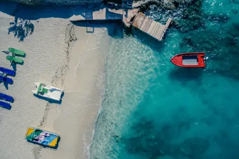 Plaża w Albanii z łodziami na piasku i w turkusowej wodzie. Jakby golem albania czekał na przygodę.