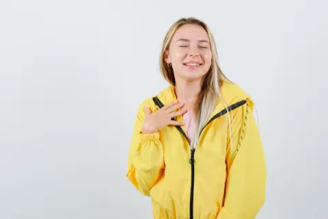 Uśmiechnięta dziewczyna w żółtej kurtce softshell. Dowiedz się, jak prać softshell, by zachować jego właściwości.