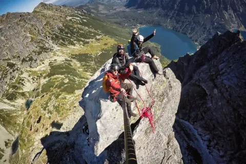 Trzech wspinaczy świętuje wejście na Mnicha. W tle jezioro i góry.
