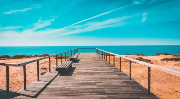 Drewniany pomost prowadzi do oceanu. Idealne miejsce, by sprawdzić, jaka jest portugalia temperatura wody i zanurzyć się w błękit.
