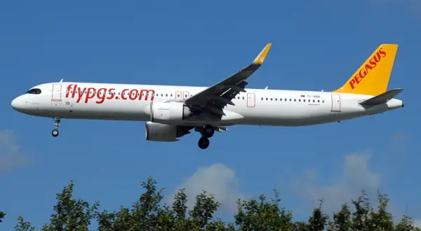 Samolot Pegasus Airlines z napisem "flypgs.com" na kadłubie, gotowy do lądowania. W bagażniku rejestrowanym czeka na pasażerów.