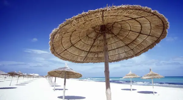 Słomiane parasole na pustej plaży w Tunezji. W marcu pogoda już zachęca do wypoczynku.