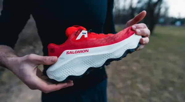 Czerwony but Salomon Ultra Glide 4 w rękach biegacza, gotowy na trailowe przygody.