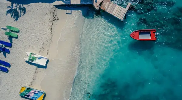 Plaża w Albanii z łodziami na piasku i w turkusowej wodzie. Jakby golem albania czekał na przygodę.