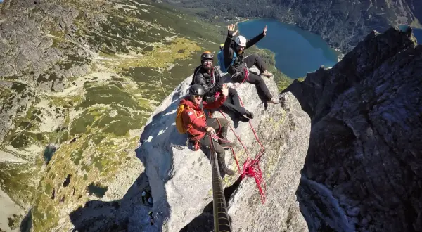 Trzech wspinaczy świętuje wejście na Mnicha. W tle jezioro i góry.