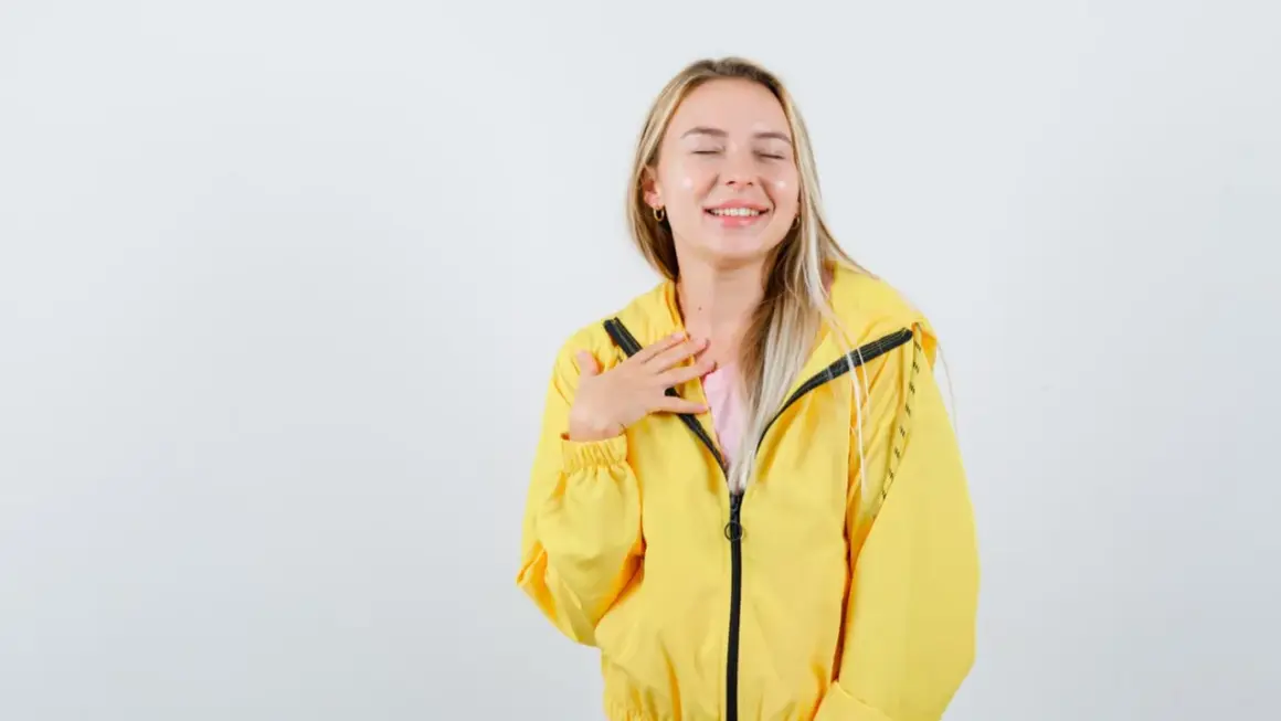 Uśmiechnięta dziewczyna w żółtej kurtce softshell. Dowiedz się, jak prać softshell, by zachować jego właściwości.