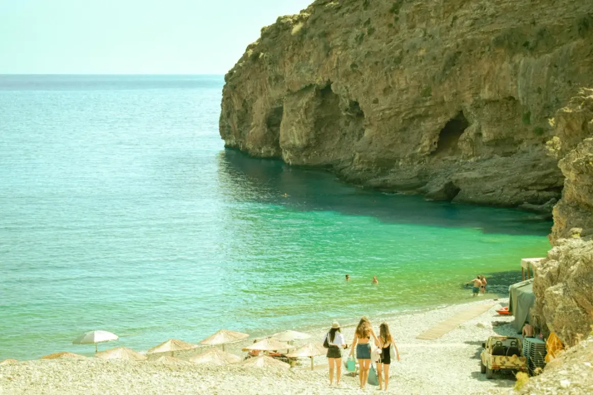 Kreta, sierpień: trzy dziewczyny idą na plażę z turkusową wodą i skalistymi klifami. Idealna pogoda na wakacje.
