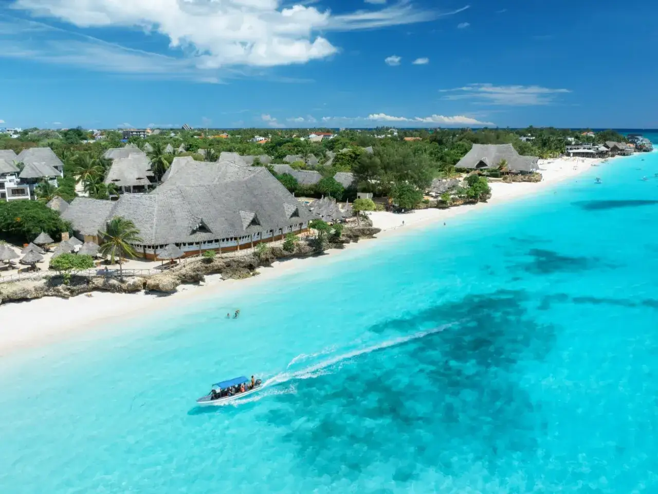Zanzibar w lutym: słoneczna plaża, turkusowa woda i ł&oacute;dź z turystami. Idealna pogoda na wakacje.