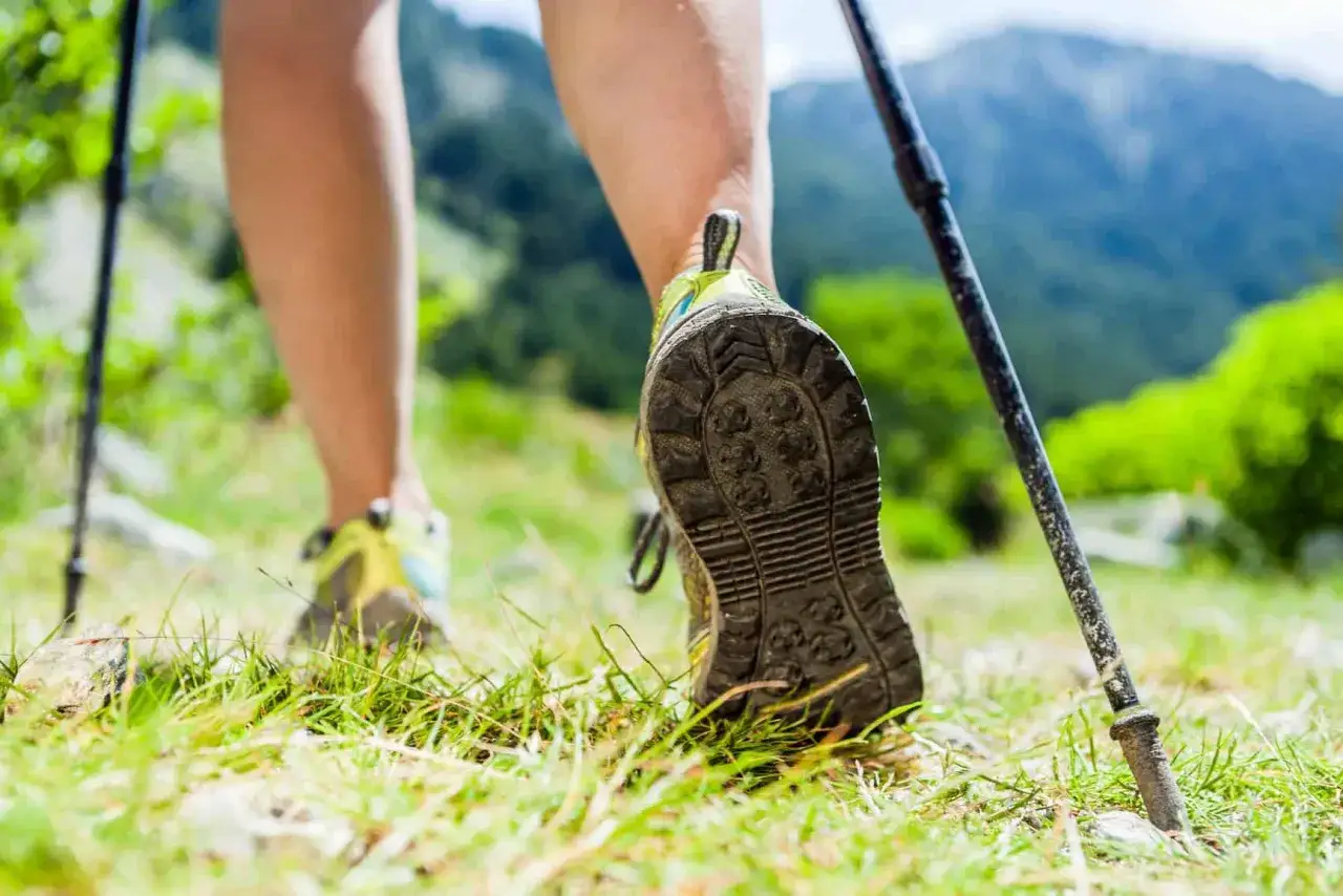 Nogi w butach do nordic walking na trawiastym szlaku. Dowiedz się, jak dobrać kije do nordic walking, by cieszyć się wędr&oacute;wką.
