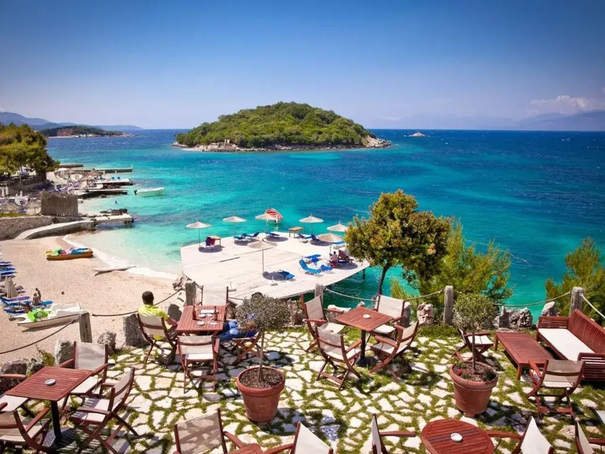 Piękna plaża w Golem, Albania, z turkusową wodą i kawiarnią na pierwszym planie.