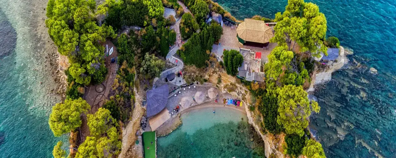 Grecja kwiecień pogoda idealna na relaks na plaży z turkusową wodą i zielonymi drzewami.