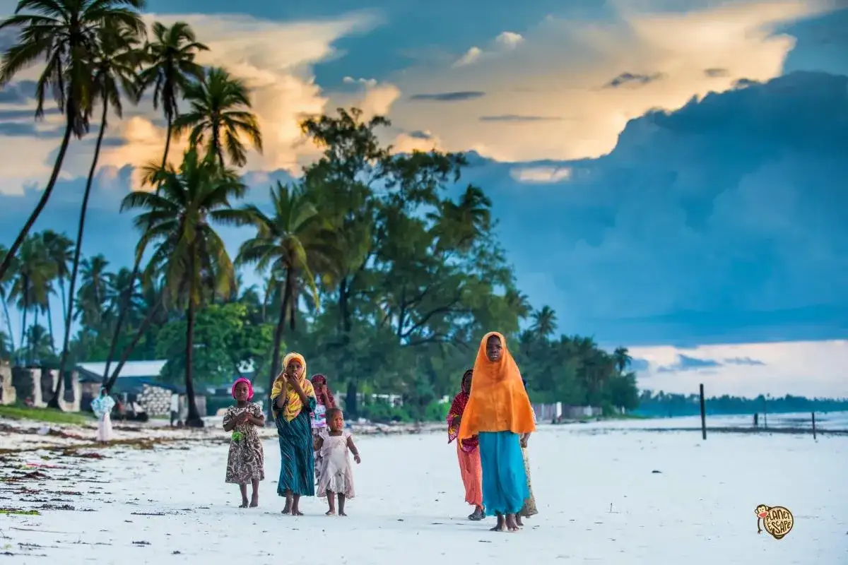 Dzieci na plaży na Zanzibarze, jesienna pogoda sprzyja spacerom. Palmy i chmury na niebie tworzą malowniczy krajobraz.