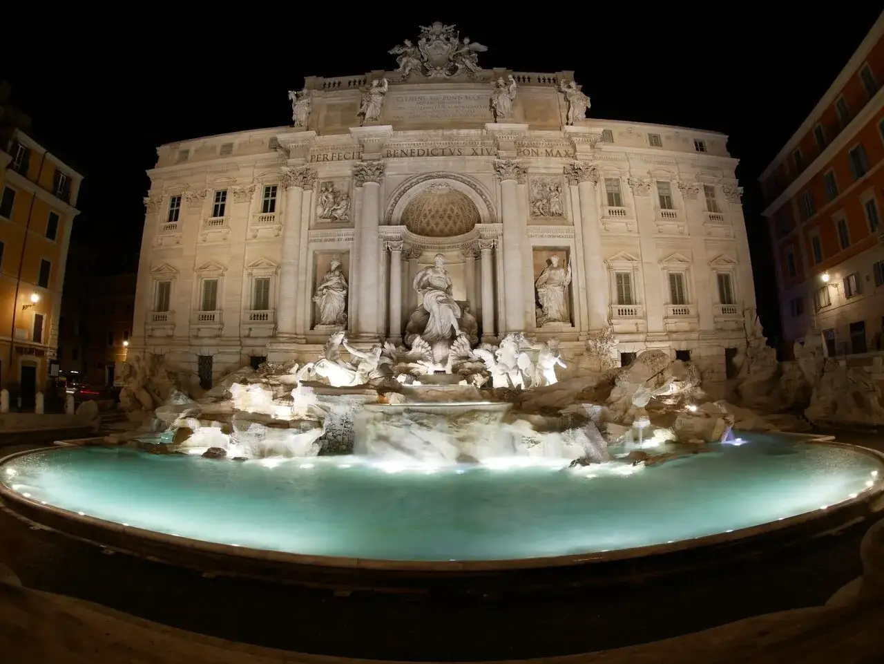 Nocna iluminacja Fontanny di Trevi w Rzymie, z turkusową wodą i rzeźbami w blasku świateł.