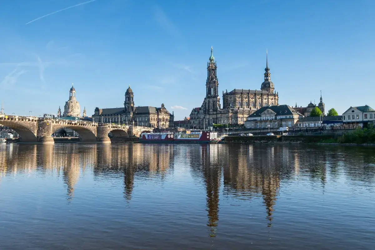 Drezno co zobaczyć: imponująca panorama miasta z mostem i zabytkowymi budowlami odbijającymi się w rzece Łabie.