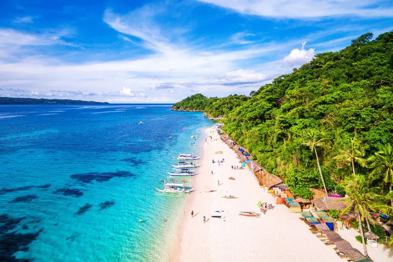 Piękna plaża na Filipinach, idealna pogoda w listopadzie. Turkusowa woda, biały piasek, palmy i łodzie.