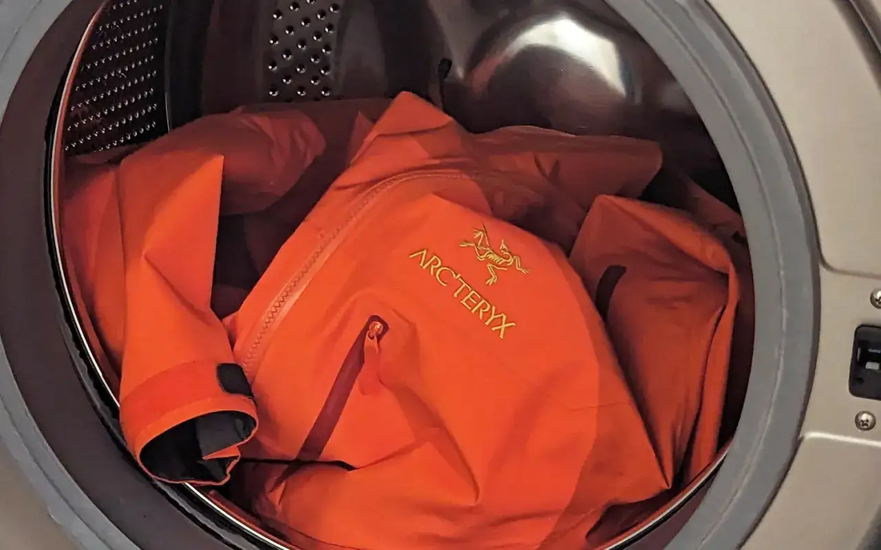 Pomarańczowa kurtka Arc'teryx w pralce. Dowiedz się, jak prać Gore-Tex, by zachować jej właściwości.