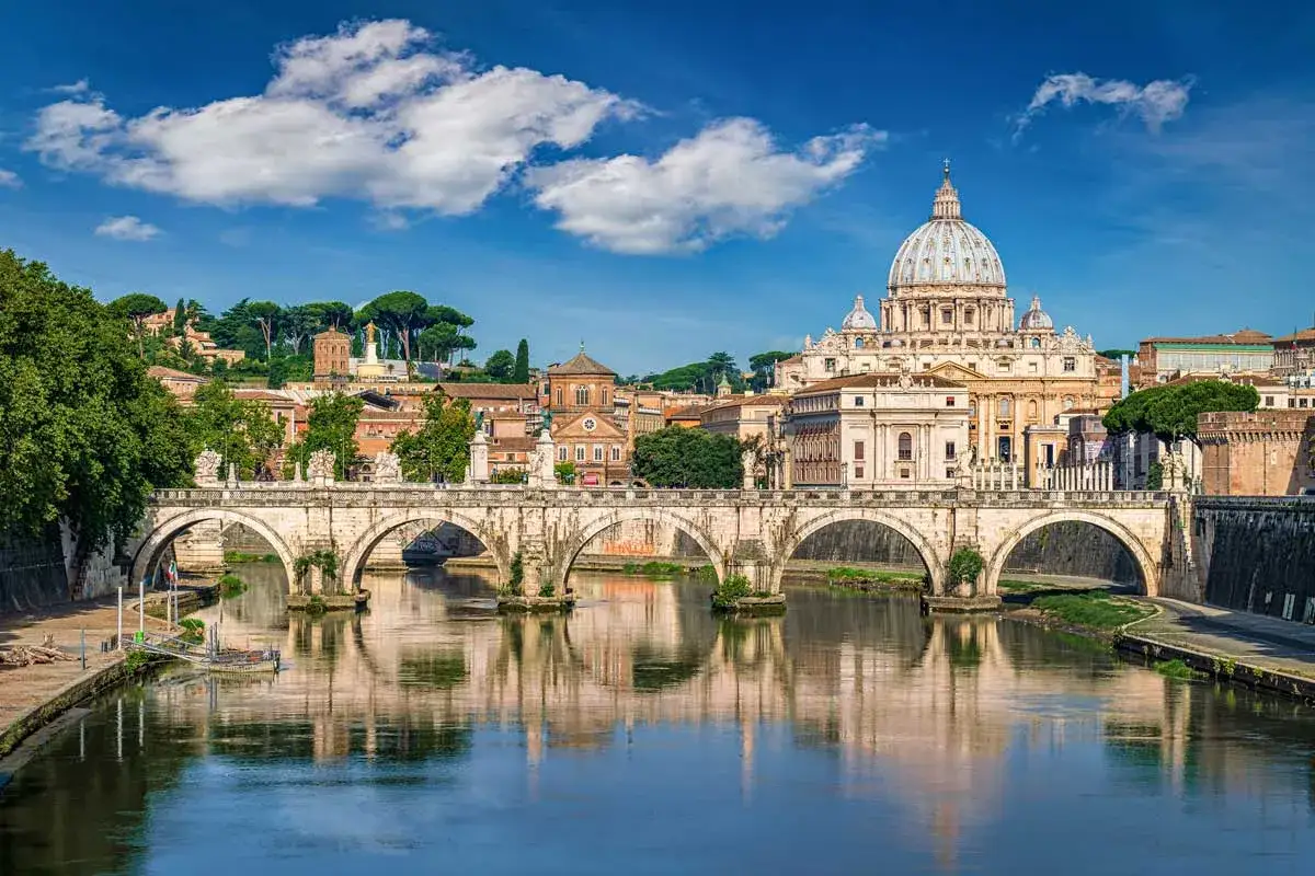 Most fascynujących ciekawostek o Włoszech: Bazylika św. Piotra w Rzymie i Ponte Sant'Angelo odbijające się w Tybrze.